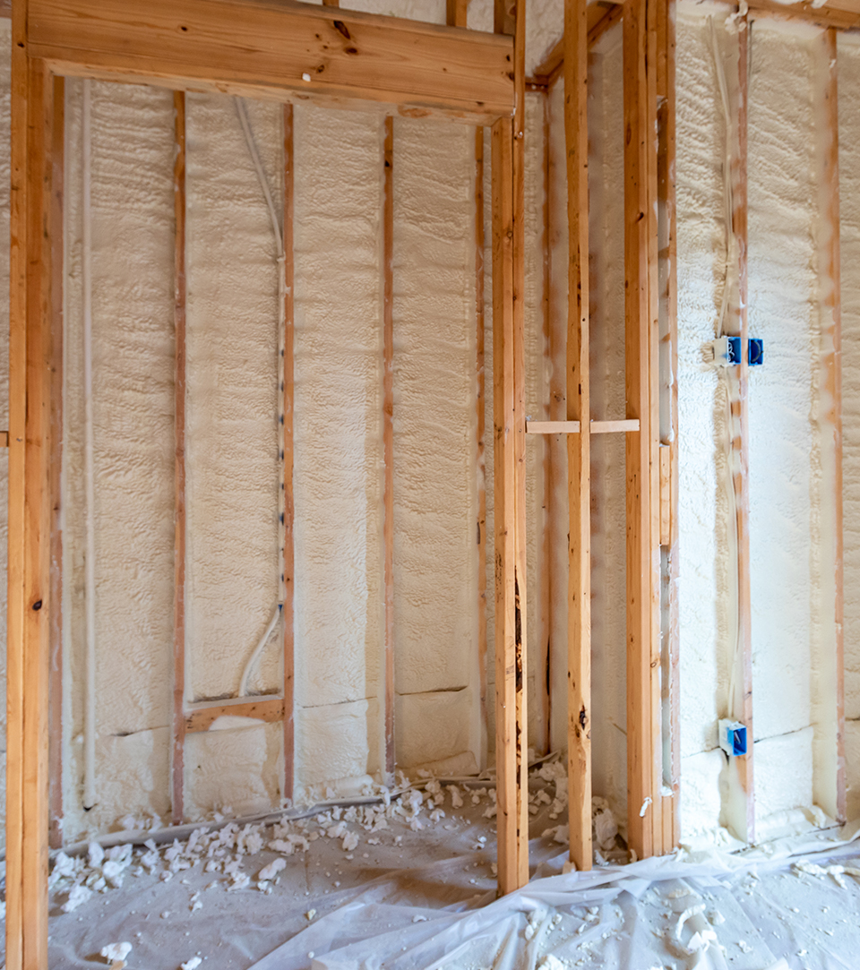 Spray foam insulation applied between wooden studs.