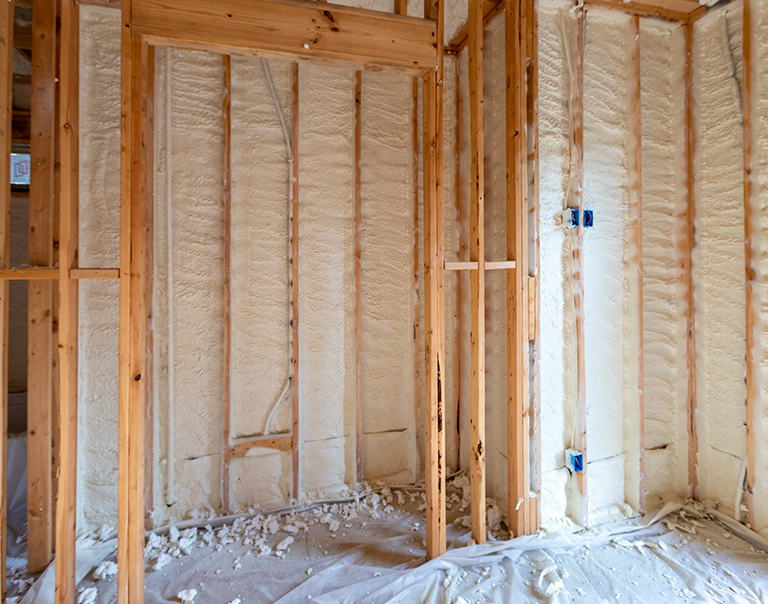 Spray foam insulation between wooden studs.